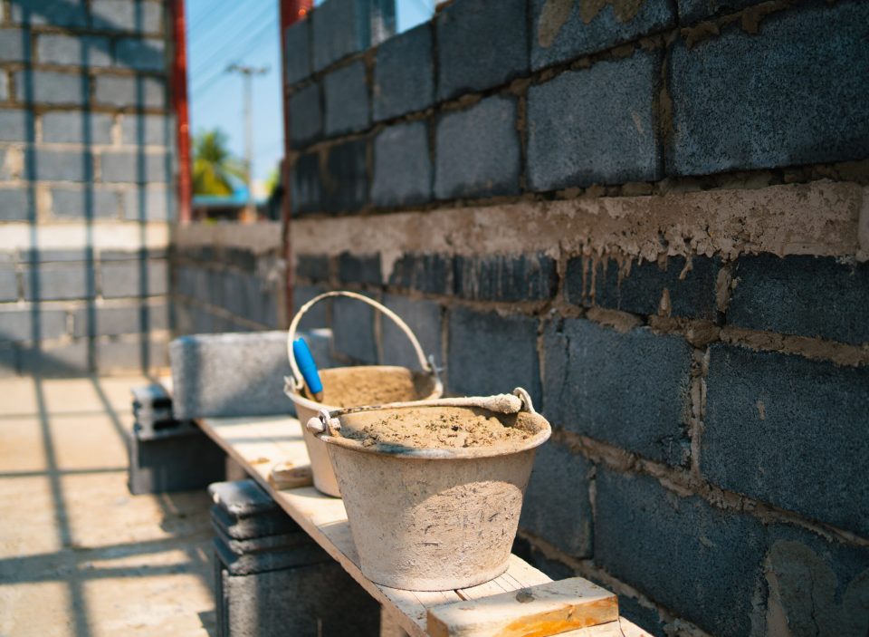 brick wall with a bucket of cement brick wall with a bucket of cement on it. The bucket is blue and has a handle